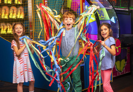 three kids holding tons of arcade tickets