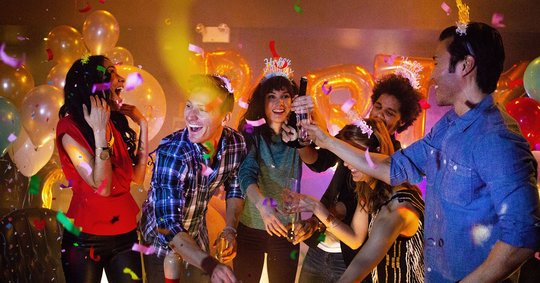 Friends opening a bottle of champagne with confetti raining down