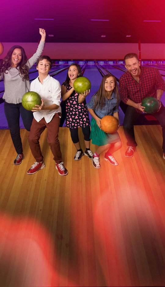 Family on the lanes holding bowling balls